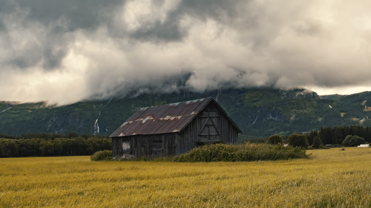 nubes oscuras que cubren una antigua casa de granero abandonada en el exuberante campo de hemsedal, noruega durante el otoño - zoom-in timelapse