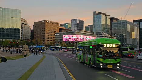 pov walking on sidewalk at seoul downtown towards gwanghwamun square with view of busy car traffic, national museum of korean contemporary history and business office building at sundown