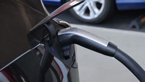 close-up sequence of a hand plugging a charger into an electric car's charging port.