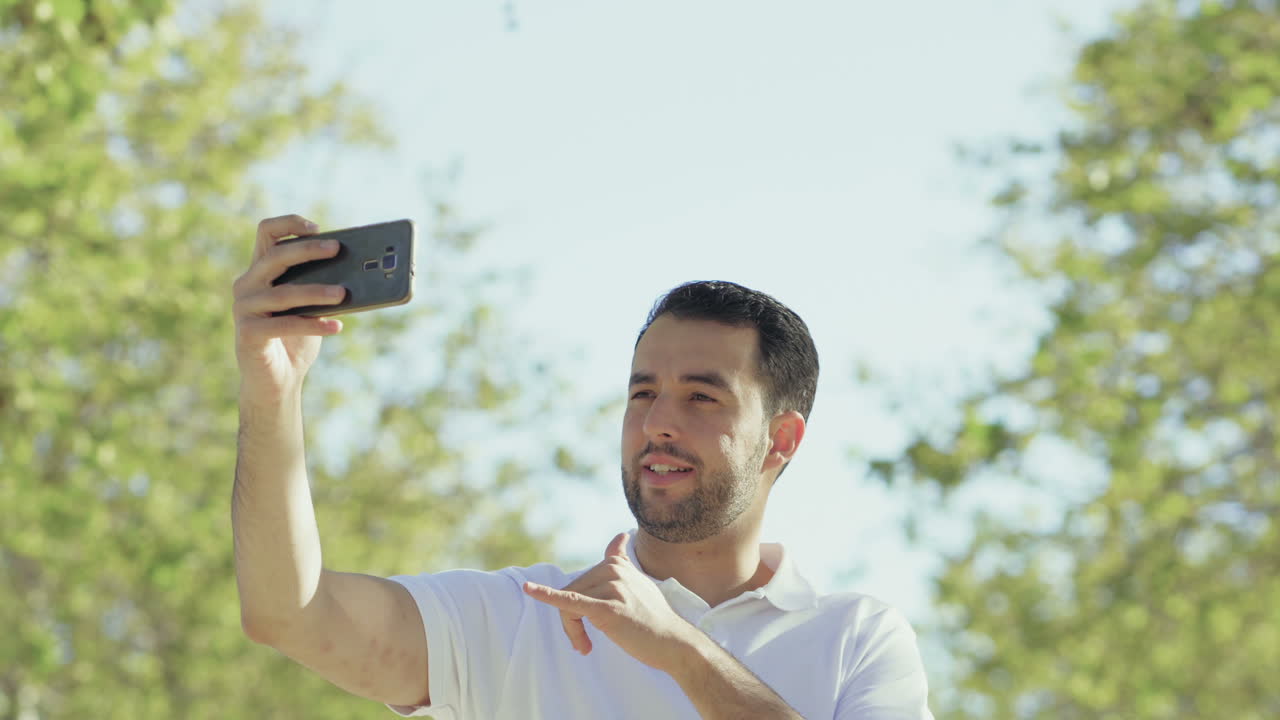 Homem jovem e bonito fazendo videochamada pelo celular.