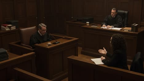a courtroom scene unfolds as a judge listens attentively to a witness on the stand, while another judge observes and takes notes, highlighting the drama of legal proceedings