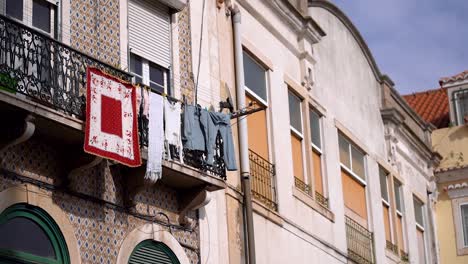 clothes drying on clothesline at balcony of old building facade, lisbon city