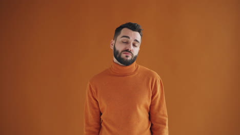 man with confused expression in orange sweater