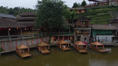 aerial drone rotating shot over lakeside hotels with tourists walking over the lake on a cloudy day in ban rak thai chinese village in thailand