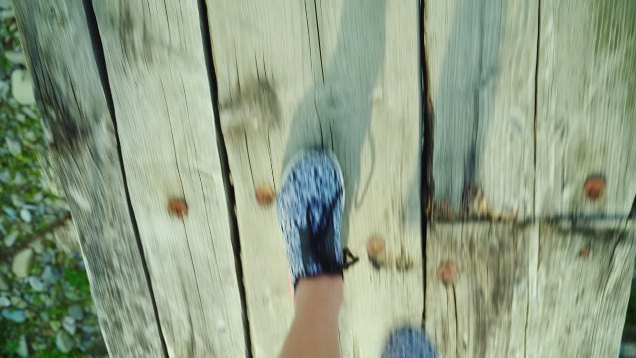 여자의 발은 산 강 위의 좁은 나무 다리를 따라 걷고 있다 위험과 출현