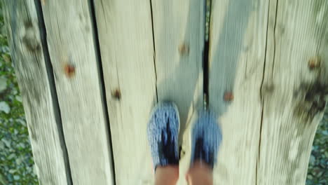 the feet of a woman are walking along a narrow wooden bridge over a mountain river danger and advent