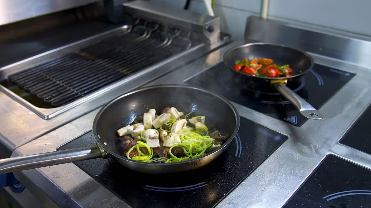 Cooking food in frying pans. Chef pouring sauce into the frying mushrooms. Making fried mixed vegetable with sauce in metal pan in the restaurant kitchen.
