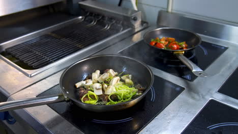 cooking food in frying pans. chef pouring sauce into the frying mushrooms. making fried mixed vegetable with sauce in metal pan in the restaurant kitchen.
