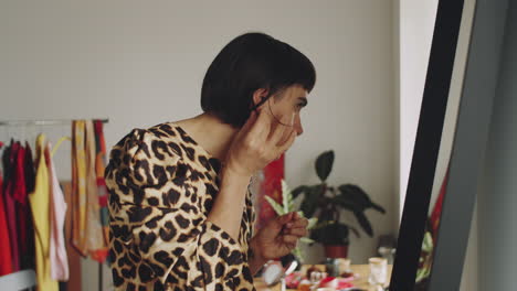 Transgender-Man-Putting-on-Earrings-at-Home