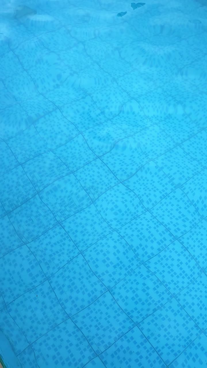 Pemandangan vertikal sudut tinggi permukaan kolam renang biru berubin yang beriak.