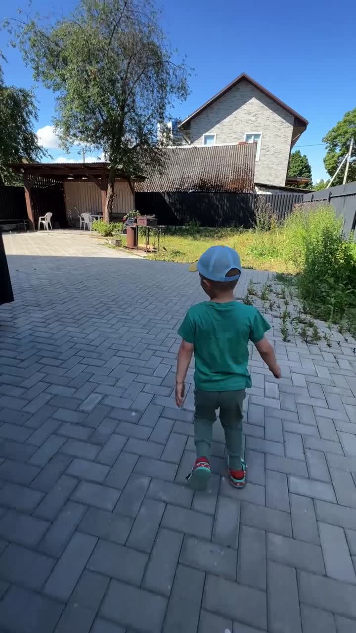 A child walks along a paved path between buildings