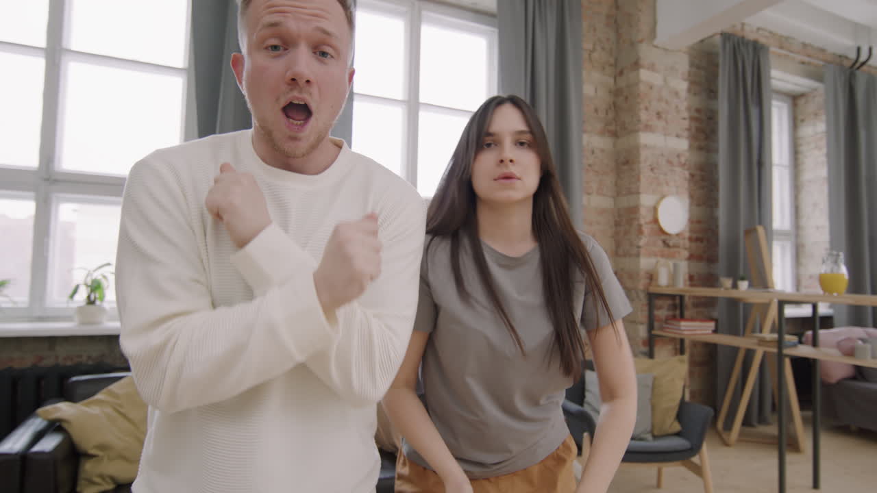 Ecstatic Young Couple Dancing and Singing before Camera