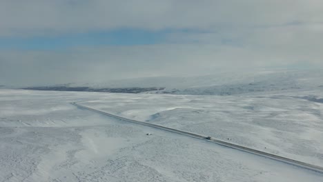 4K-drone-footage-of-car-driving-in-snowy-landscape-in-Iceland