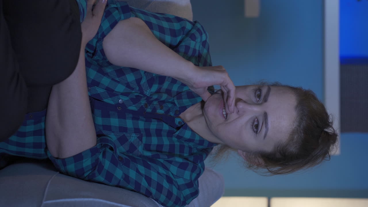 video vertical de una mujer mordiéndose las uñas por el estrés en casa por la noche.