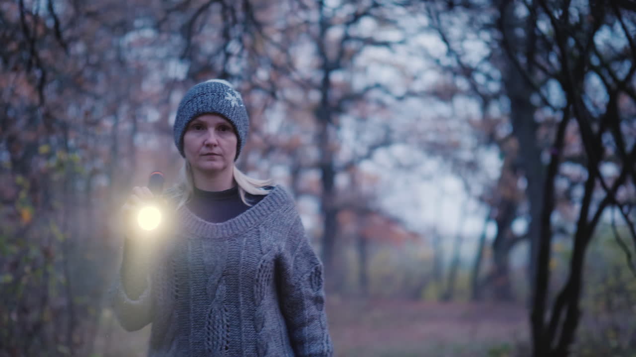 женщина с фонариком идет по темному лесу в поисках чего-то поиск промаха