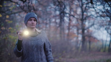 una mujer con una linterna camina por un bosque oscuro buscando algo buscando a la señorita