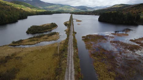 train railroad surrounded river and mountain landscape, aerial shot