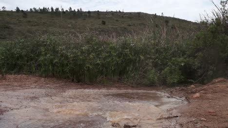 ciclistas cabalgan a través de un charco fangoso salpicando agua en un camino de grava