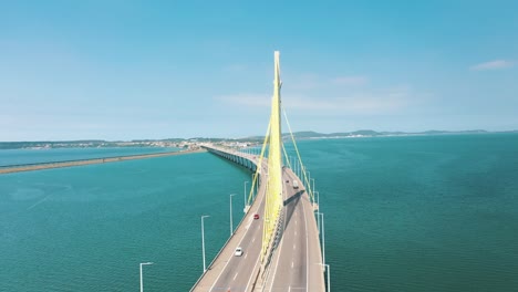 cinematic orbital aerial shot bridge above the turquoise color ocean, located in laguna, santa catarina, brazil