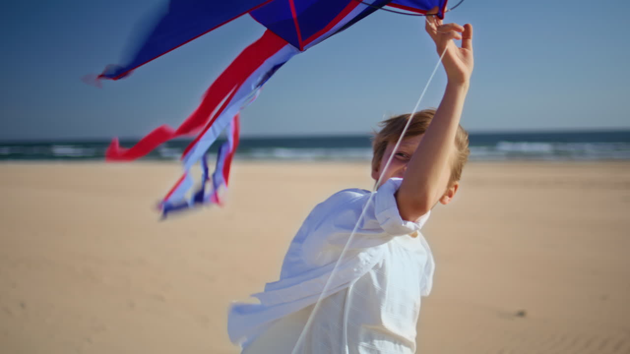 Happy boy launching kite on windy beach closeup. Smiling child playing