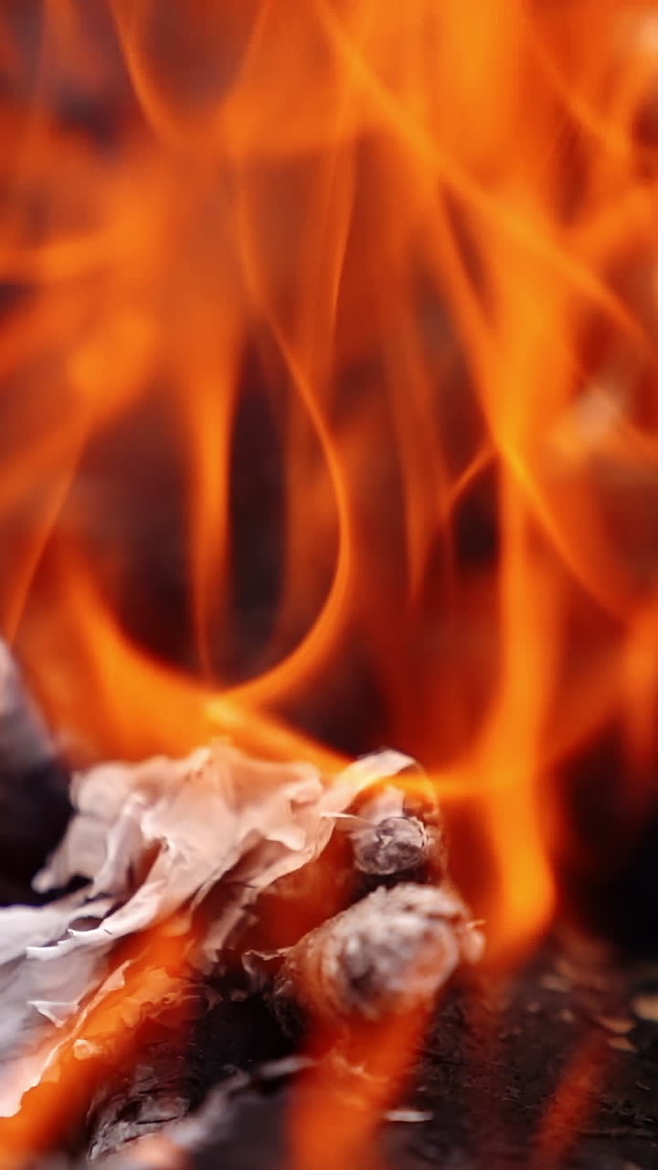 Legna da ardere bruciata nel fuoco. Sfondo luminoso di fiamme arancioni ardenti, primo piano.