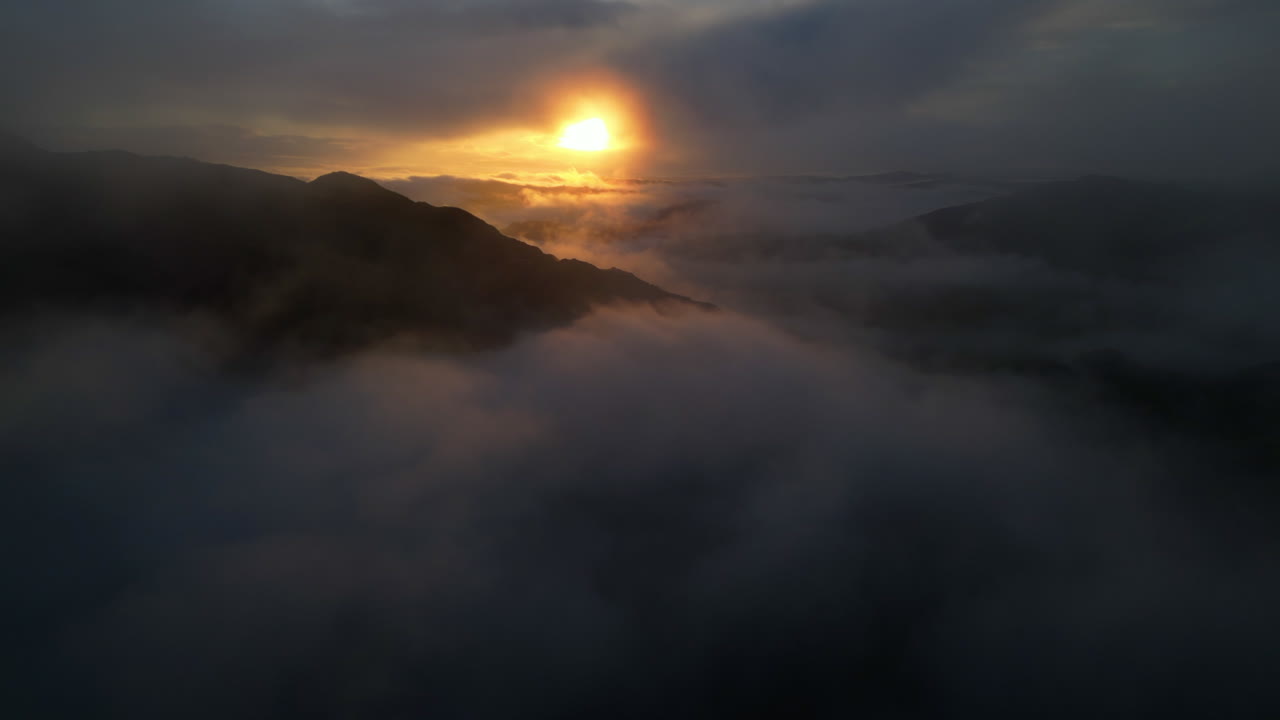 amanecer sobre nubes envueltas en siluetas de montaña con una lenta retirada en nubes finas