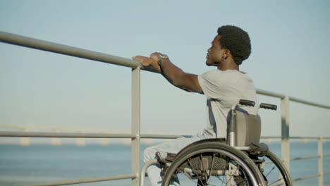 young black man in wheelchair enjoying sea view