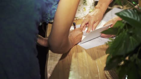 shot of the bride and groom signing the marriage contract at the wedding party