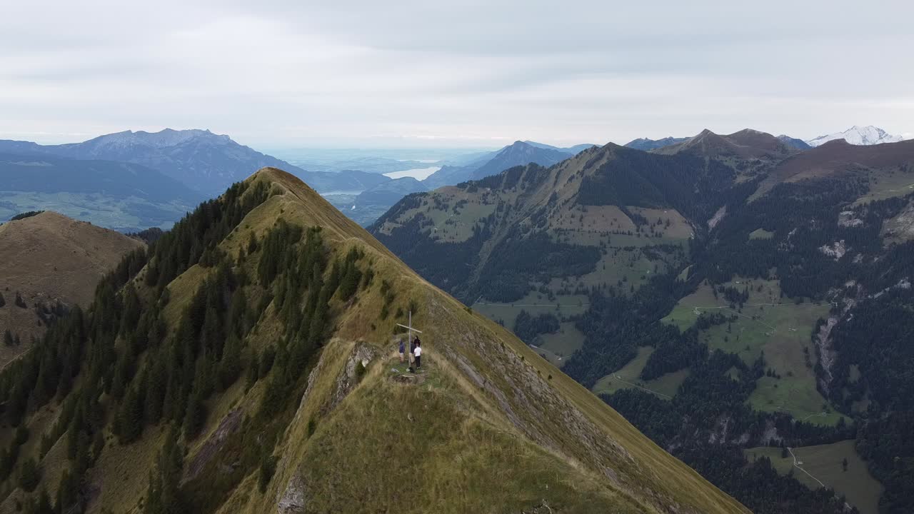 volando sobre la cruz en la cima de una montaña suiza con los alpes al fondo
