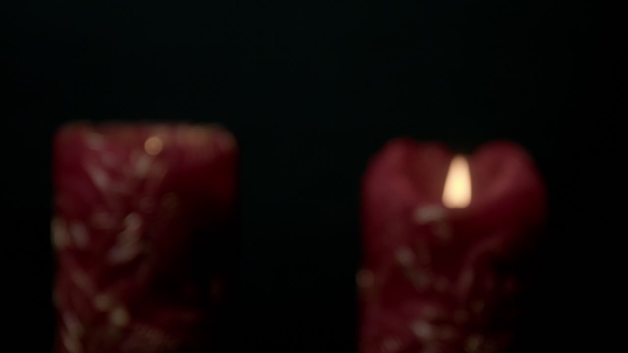 Detailed view of a burning red candle with intricate decorative designs against a dark background, creating a warm and intimate atmosphere. Perfect for relaxation or meditation visuals