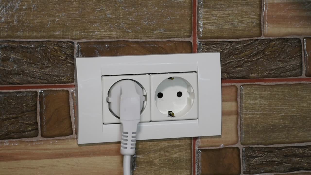 벽면 전원 소켓에 꽂고 뽑는 여성 손의 정면 모습