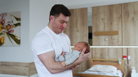 strong caucasian man hold a tiny newborn on his hand. little child sleeps peacefully in father's arms.