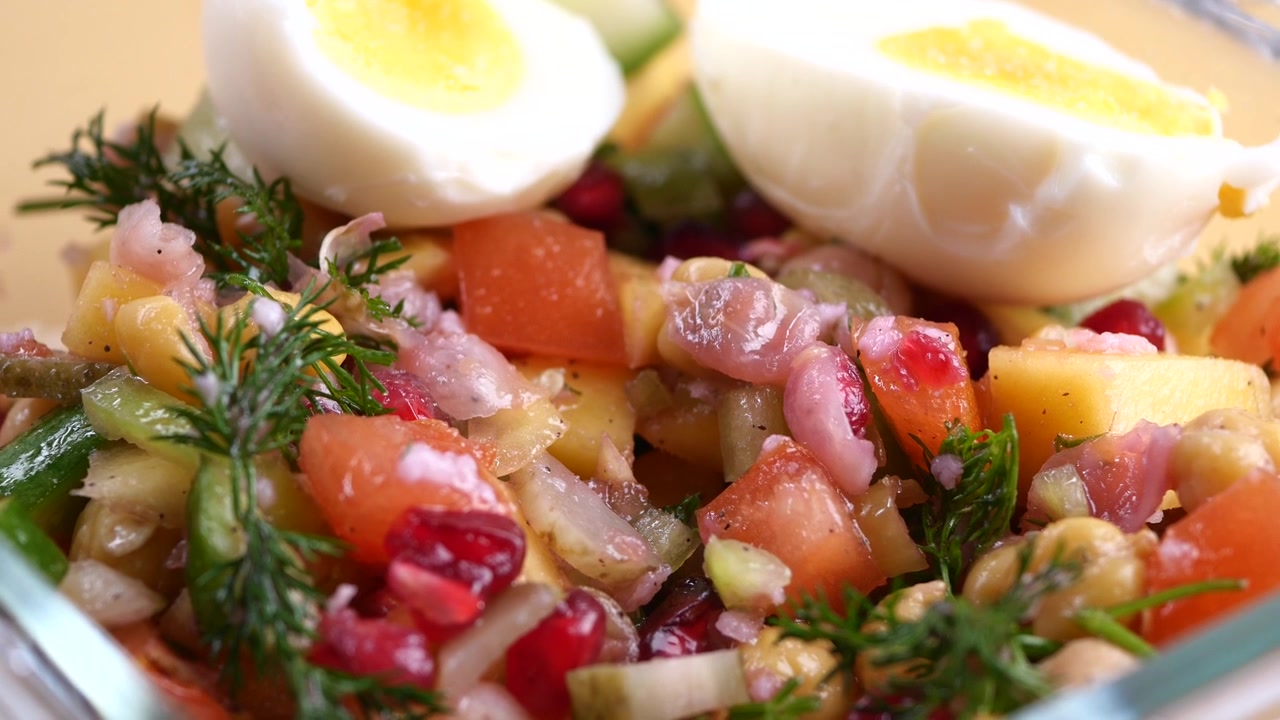 Insalata fresca di verdure con uovo sodo in una ciotola di vetro.