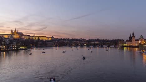 Lapso-De-Tiempo-De-Botes-De-Remo-En-El-Río-Vltava-En-Praga-Con-El-Castillo-Y-El-Puente-Charles-En-El-Fondo,-Vista-Estática-De-4k