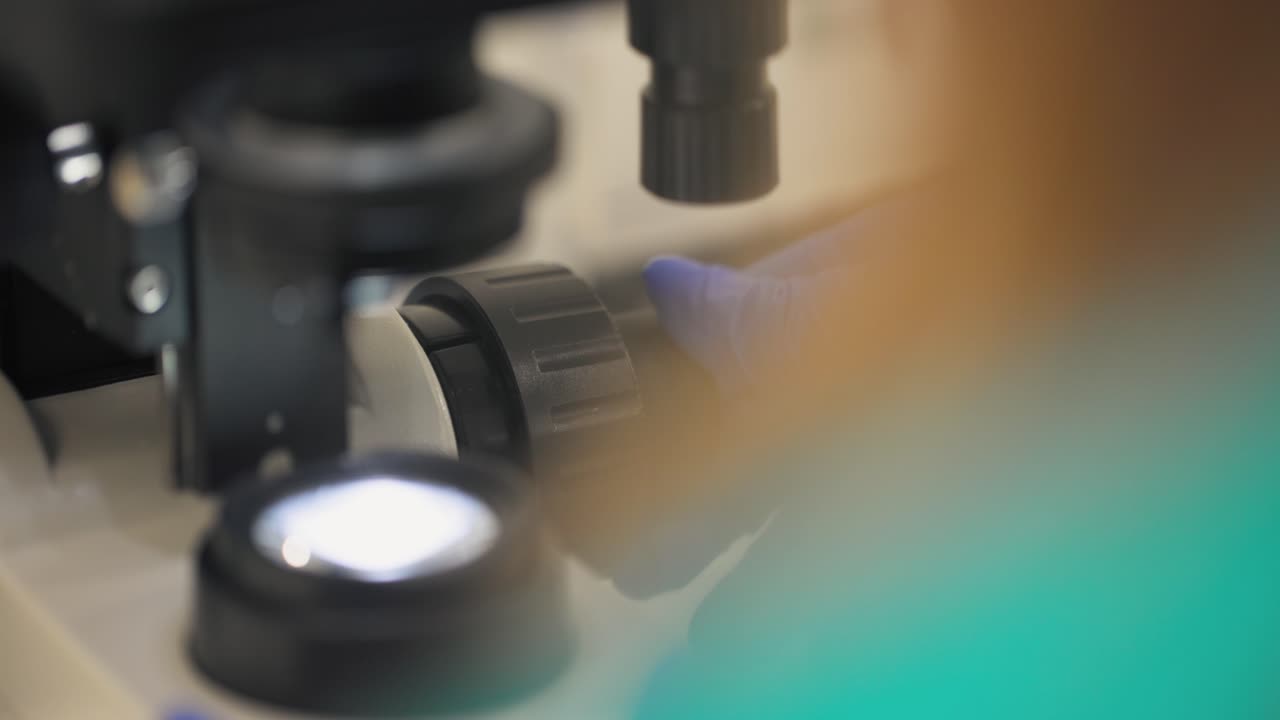 임상 의사 가 현미경 에 초점을 맞추기 위해 손잡이 를 조정 하고 있다