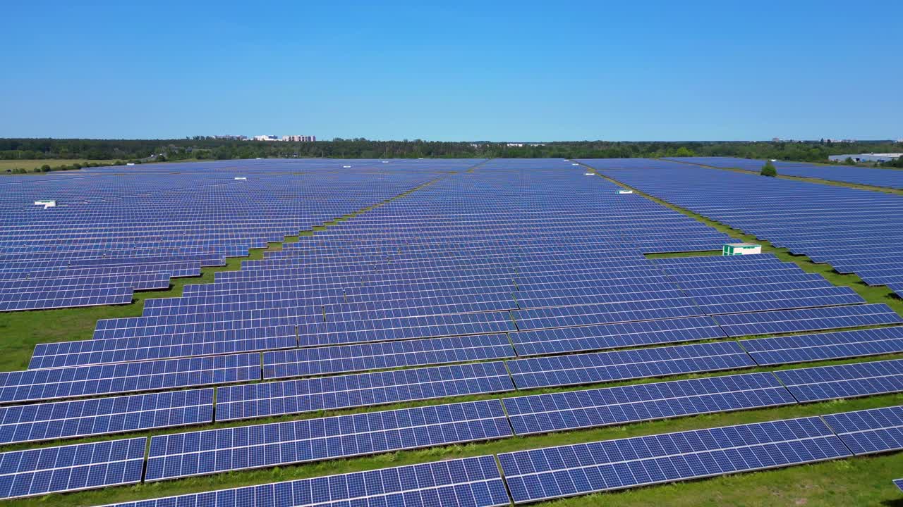Rows of photovoltaic solar panels are absorbing the sun in a large power station under a clear blue sky. Great aerial view flight drone shot footage from above