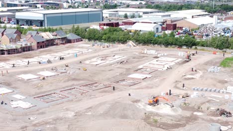 UK-town-housing-development-land-working-foundation-construction-site-aerial-view-orbit-left