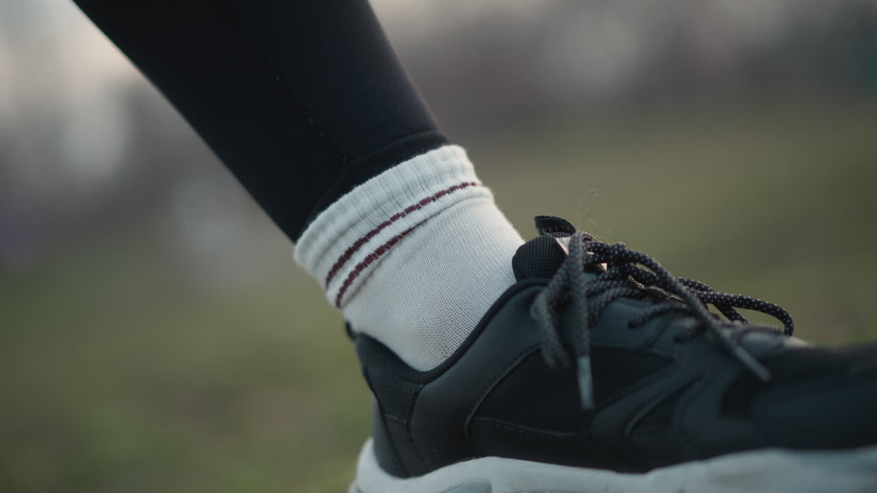 Athlete Getting Ready, Closeup Of Athlete Preparing In Park At Twilight With Accessories Visible, Distinctive Image Of Hands Fixing Sock On Ankle During Evening Workout Session In Grassy Park
