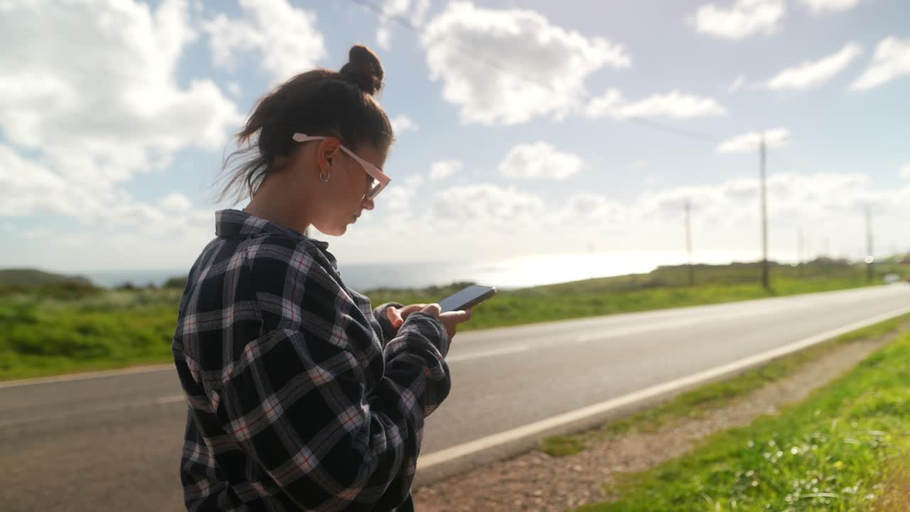 Giovane donna che usa il telefono all'aperto vicino a una strada