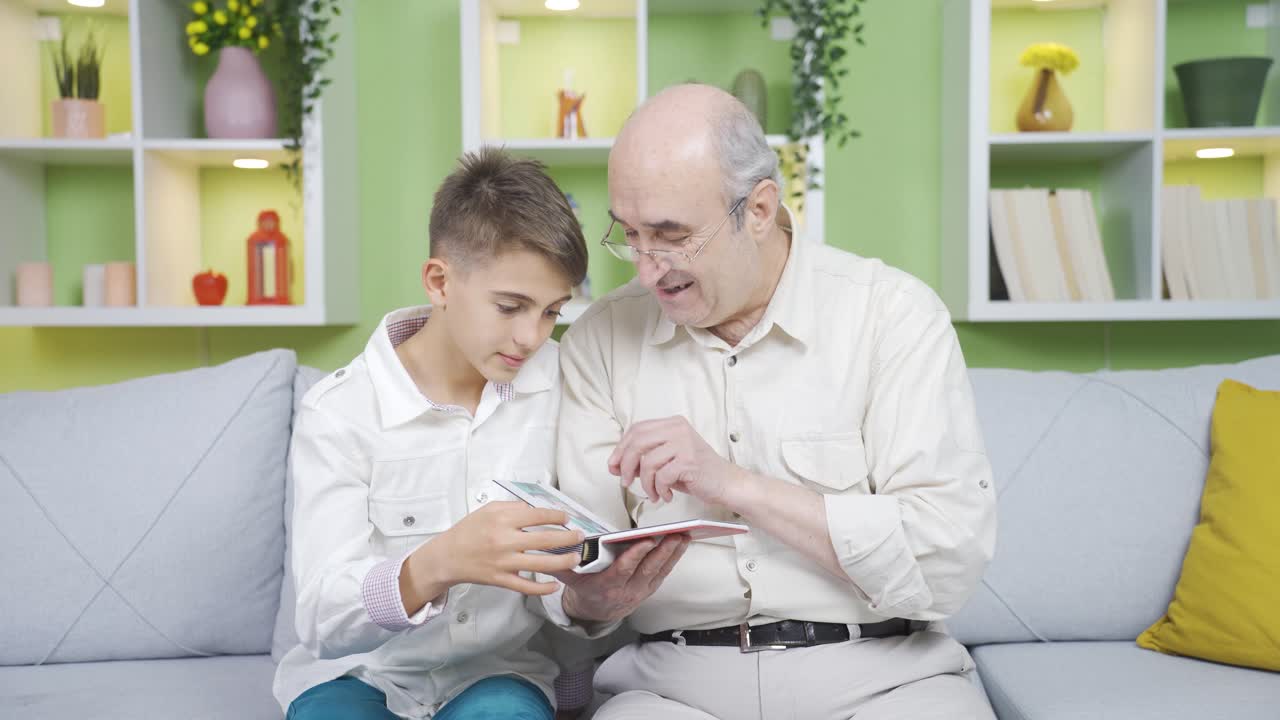 Grandfather examines his old photo album candidly with his grandson.