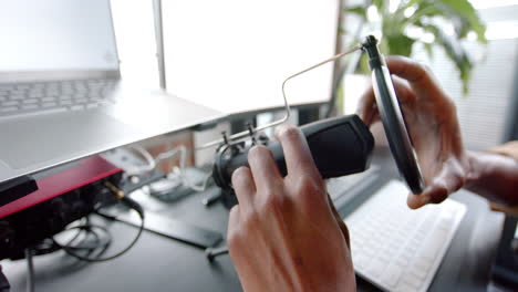 Happy-african-american-man-setting-up-microphone-for-live-podcast-at-home,-slow-motion