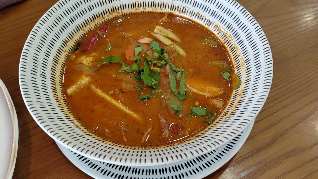 A bowl of mixed Tom Yum soup, a popular dish from Thailand. This spicy and sour dish is a favorite in Malaysia, known for its vibrant flavors and aromatic herbs