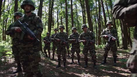 low-angle video of soldiers in camouflage walking through a dense forest, emphasizing the towering
