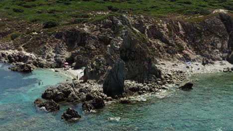 Dolly-Out-Toma-Aérea-De-Una-Playa-Estrecha-En-La-Isla-Mediterránea-Italiana-De-Cerdeña