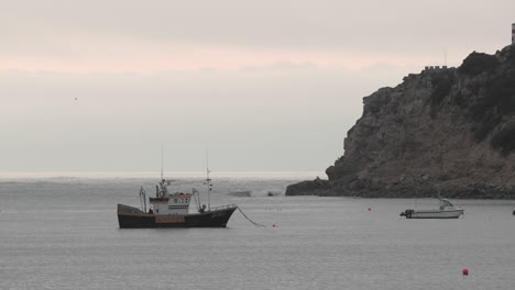 Solitary-Boat-Sailing-By-The-Beach-Of-Sao-Martinho-Do-Porto-Caldas-Da-Rainha-Portugal---wide-shot