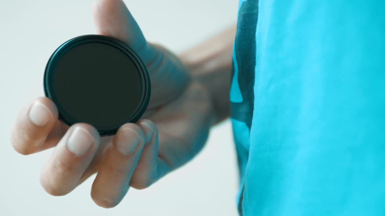 CAMERAS, LENSES, FILTERS, FLASHES, CAPS FILM ARE PILED UP, ON A MATTE BLACK TABLE TOP. FROM OVERHEAD THIS FORGOTTEN PHOTO GEAR CREATES A BEAUTIFUL TRACKING SHOT.