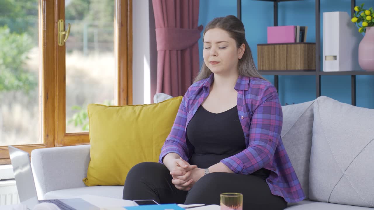 행복한 젊은 여자는 창문 밖을 바라보고 깊은 숨을 쉬고 있습니다.