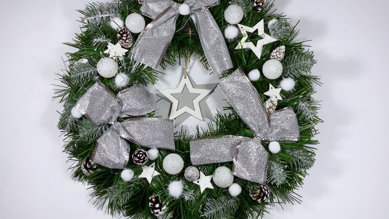 크리스마스 문 앞을 장식하는 크리스마스 꽃받침은 색 배경에 고립 된 스프루스, 은 활, 별 및 크리스마스 공으로 만들어졌습니다.