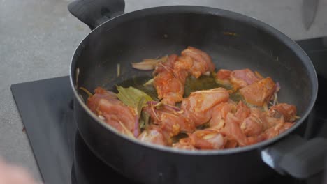 pollo cocinado en una sartén con cebollas y hoja de laurel