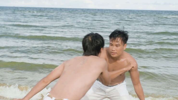 Two men dancing capoeira on the beach